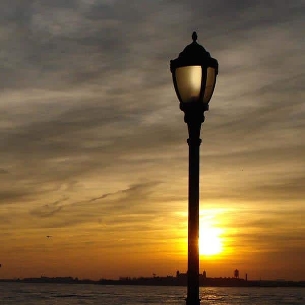 una luz en Nueva York LED acrylic globe with large cap and arms post top luminaire with finial overlooking river at sunset