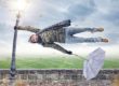 man holding onto street light during wind storm