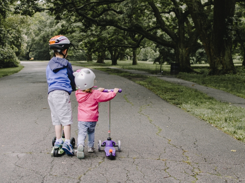 two children riding scooters on trail