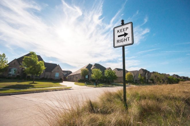 Keep right sign next to road and houses.