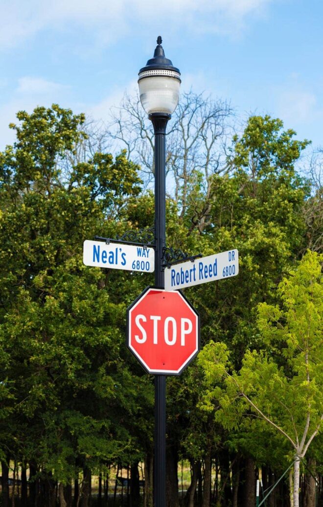 LED traditional post-top luminaire with street signs and a stop sign.