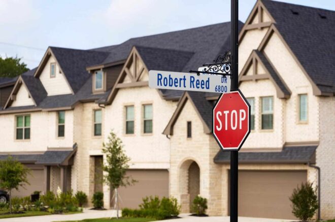 Street signs and a stop sign mounted on a channel pole in a residential area.