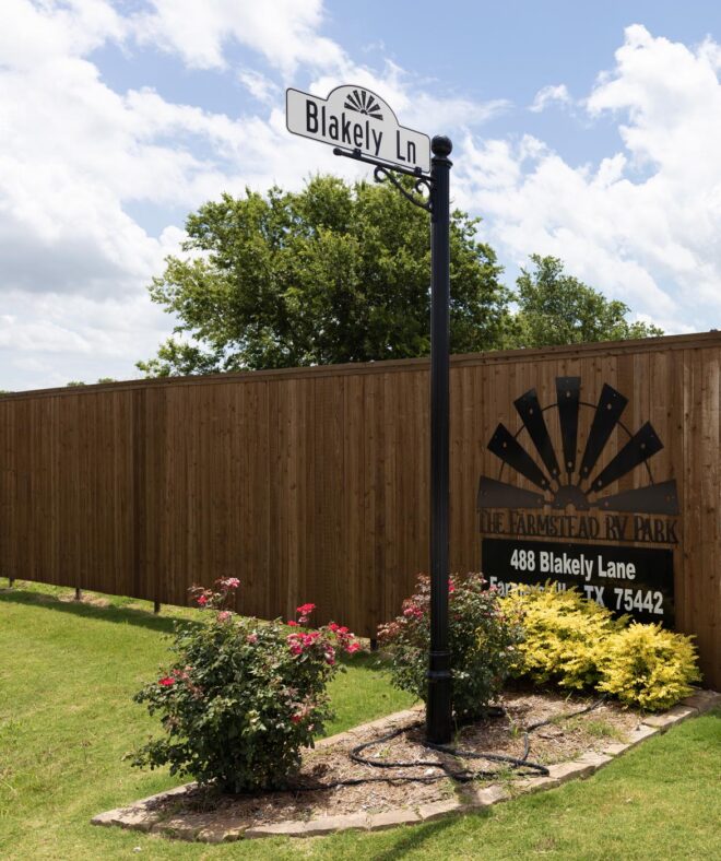 Street sign with a round channel pole and a decorative base inside of The Farmstead RV Park.