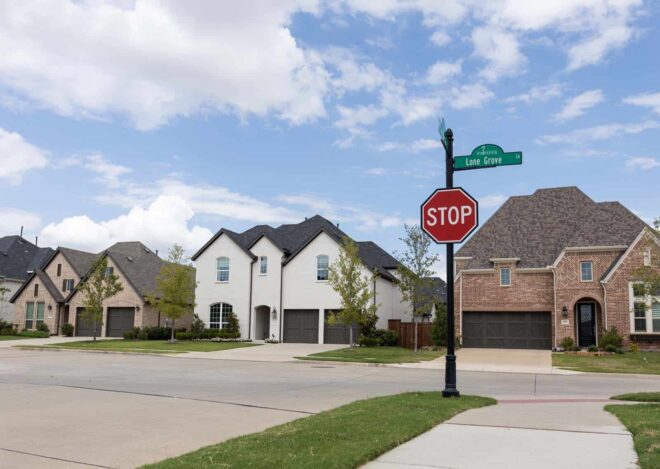 Street sign/Stop sign combo on a round pole with an acorn finial top in front of residential homes.