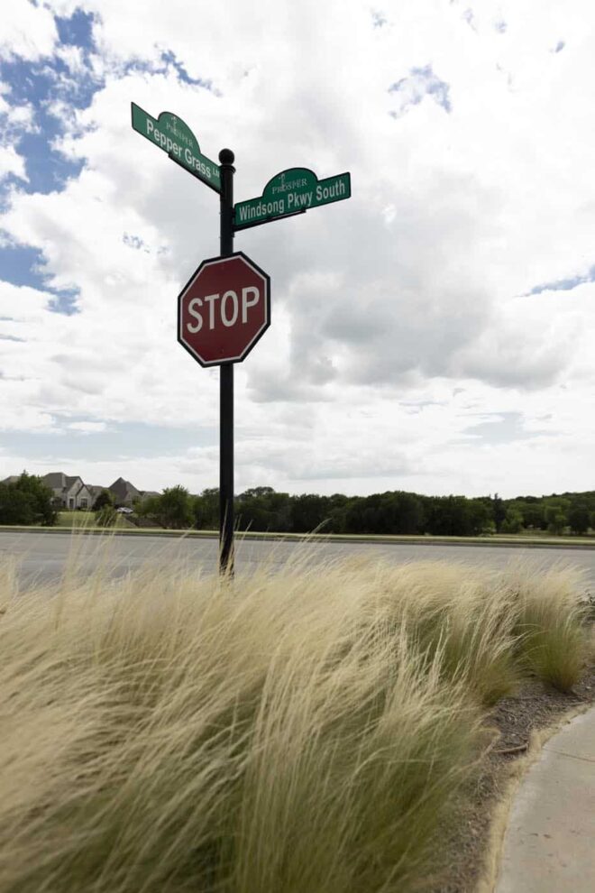 Street sign/Stop sign combo with a round decorative finial top in a residential area.