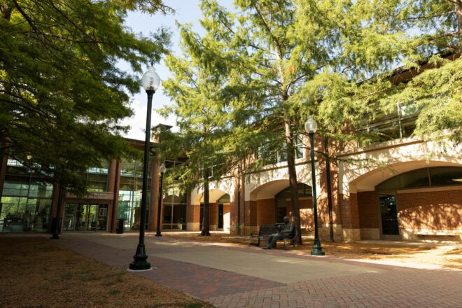 Two traditional post-top luminaires, AC Series, line a pathway outside of a public library.