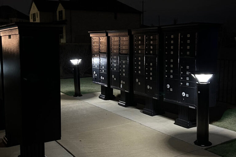 Solar Efficiency Two solar bollards illuminate a row of cluster mailbox units after dark.